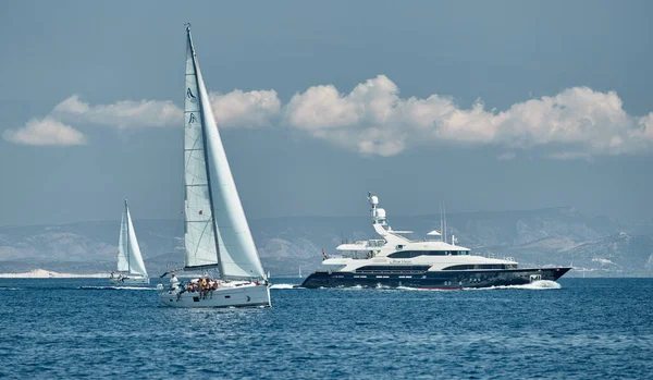 Croacia, Mar Adriático, 17 Septiembre 2019: La carrera de veleros, el equipo se sienta en el borde de un barco a bordo, una regata, El gran yate de motor pasa detrás, la isla está en el fondo — Foto de Stock