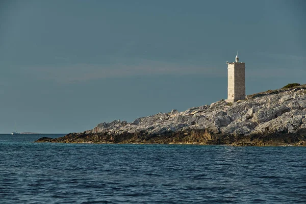 O farol na ilha na Croácia perto de Vis ao pôr-do-sol, uma costa rochosa, escada para um farol, uma pequena capa — Fotografia de Stock