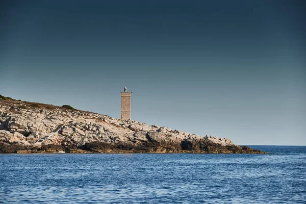 Der Leuchtturm auf der Insel in Kroatien in der Nähe von Vis bei Sonnenuntergang, eine felsige Küste, Leiter zu einem Leuchtturm, ein kleines Kap — Stockfoto