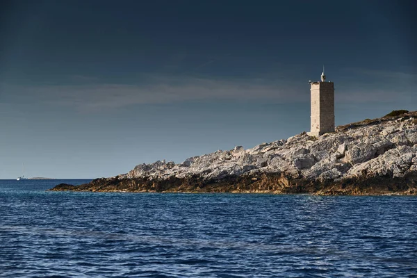 O farol na ilha na Croácia perto de Vis ao pôr-do-sol, uma costa rochosa, escada para um farol, uma pequena capa — Fotografia de Stock