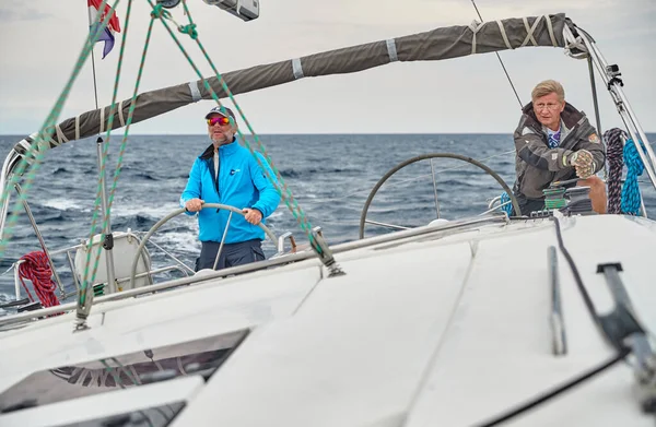 Croacia, Mar Adriático, 19 de septiembre de 2019: La carrera de veleros, el equipo se sienta en el borde de un barco a bordo, el trabajo en equipo, lucha intensa, colores brillantes, otros participantes de la carrera en un fondo — Foto de Stock