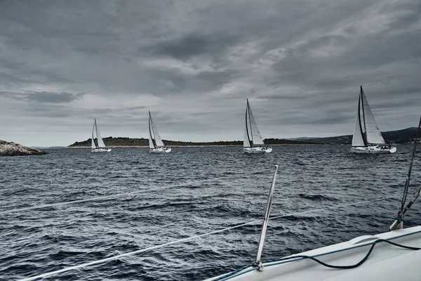 Kroatien, Adria, 19. September 2019: Das Rennen der Segelboote, das Team sitzt am Rand eines Bootsbretts, helle Farben, Blick auf die Teilnehmer des Rennens von anderen Boot durch Seile und Segel — Stockfoto