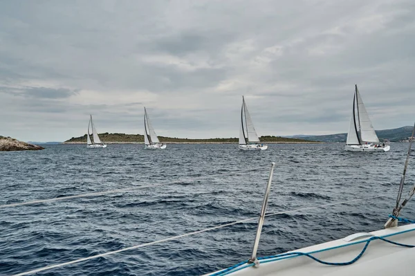 Croácia, Mar Adriático, 19 de setembro de 2019: A corrida de veleiros, a equipe fica à beira de uma placa de barco, cores brilhantes, vista dos participantes da corrida de outro barco através de cordas e velas — Fotografia de Stock