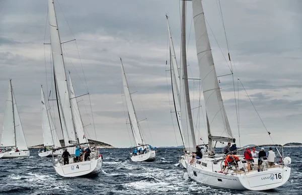 Croatia, Adriatic Sea, 19 September 2019: The race of sailboats, the team sits on the edge of a boat board, team work, intense fight, bright colors, other participants of race on a background — Stock Photo, Image