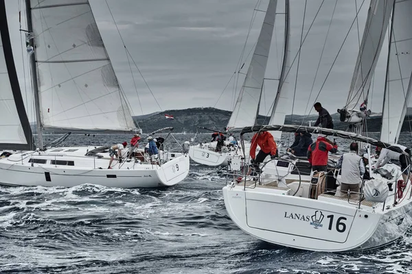 Croatia, Adriatic Sea, 19 September 2019: The race of sailboats, the team sits on the edge of a boat board, team work, intense fight, bright colors, other participants of race on a background — Stock Photo, Image