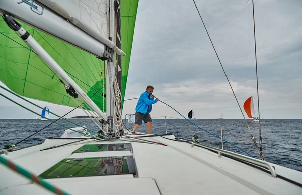 Croacia, Mar Adriático, 19 de septiembre de 2019: La carrera de veleros, el equipo se sienta en el borde de un barco a bordo, el trabajo en equipo, lucha intensa, colores brillantes, otros participantes de la carrera en un fondo — Foto de Stock