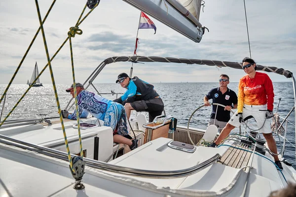 Croacia, Mar Adriático, 19 de septiembre de 2019: La carrera de veleros, el equipo se sienta en el borde de un barco a bordo, el trabajo en equipo, lucha intensa, colores brillantes, otros participantes de la carrera en un fondo — Foto de Stock