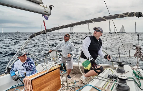 Croacia, Mar Adriático, 19 de septiembre de 2019: La carrera de veleros, el equipo se sienta en el borde de un barco a bordo, el trabajo en equipo, lucha intensa, colores brillantes, otros participantes de la carrera en un fondo — Foto de Stock