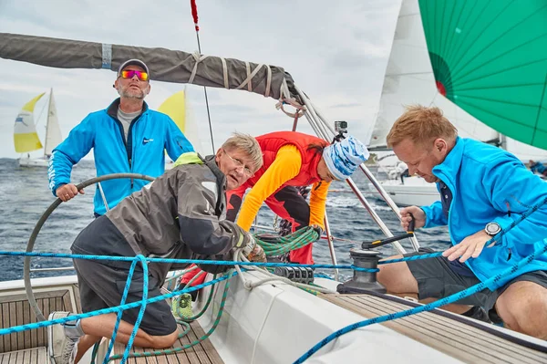 Croacia, Mar Adriático, 19 de septiembre de 2019: La carrera de veleros, el equipo se sienta en el borde de un barco a bordo, el trabajo en equipo, lucha intensa, colores brillantes, otros participantes de la carrera en un fondo — Foto de Stock