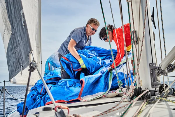 Croacia, Mar Adriático, 19 de septiembre de 2019: La carrera de veleros, el equipo puso un spinnaker a bordo del barco, trabajo en equipo, lucha intensa, colores brillantes, otros participantes de la carrera sobre un fondo — Foto de Stock