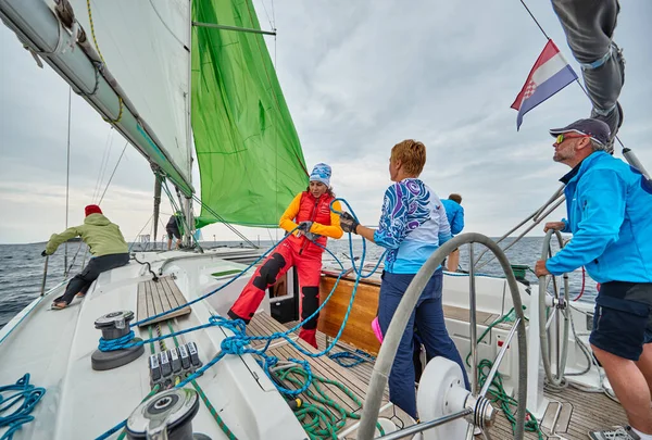 Croácia, Mar Adriático, 19 de setembro de 2019: A corrida de veleiros, a equipe fica à beira de um tabuleiro de barco, trabalho em equipe, luta intensa, cores brilhantes, outros participantes da corrida em um fundo — Fotografia de Stock