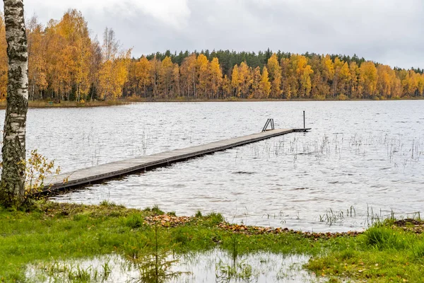 Długi pomost na jeziorze, taras nad jeziorem, jesień nad jeziorem Boroye, Łodzie na molo, Valday park narodowy, Rosja, panoramiczny obraz, złote drzewa, drewniane domki, zachmurzona pogoda — Zdjęcie stockowe
