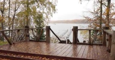 Göldeki uzun iskele, göldeki teras, Boroye Gölü 'ndeki sonbahar, rıhtımdaki botlar, Valday Ulusal Parkı, Rusya, panoramik görüntü, altın ağaçlar, ahşap kulübeler, bulutlu hava.