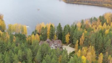 Sonbaharda Boroye Gölü, ormandaki büyük ahşap ev, göl kıyısındaki rıhtım, Valday Ulusal Parkı, Rusya, panoramik görüntü, altın ağaçlar, ahşap pansiyonlar, bulutlu hava.
