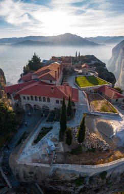 Manastır Trinity 'nin havadan görünüşü ve gün batımında Meteora vadisi ve tarihi kanyonunun nefes kesici resimleri, Kalambaka, Yunanistan, gölgeler, çarpık yollar, sütun gibi dağlar