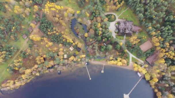Voo sobre a casa, ponto de vista drone da área rural no outono com lago Boroye, A grande casa de madeira na floresta, Piers no lago, Valday National Park, Rússia, árvores douradas, alojamentos de madeira, lagoas — Vídeo de Stock