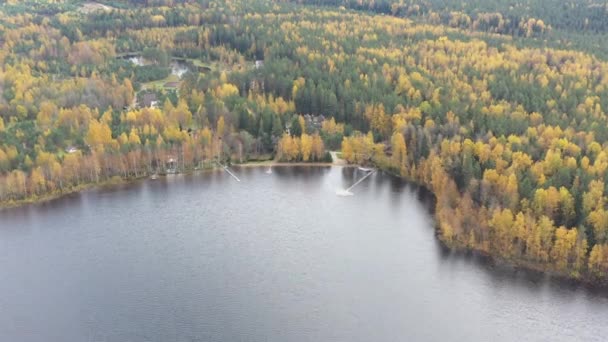 Punto de vista del dron de la zona rural en otoño con el lago Boroye, La gran casa de madera en el bosque, Muelles en el lago, Parque Nacional de Valday, Rusia, árboles de oro, logias de madera, estanques, tiempo nublado — Vídeo de stock