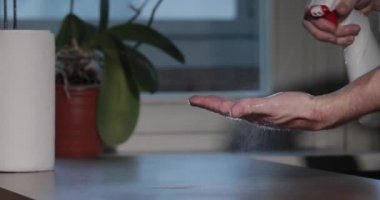 Adam dezenfektanla el temizliyor, şişe spreyine bastırıyor, kağıt havlu rulosu yapıyor, Coronavirüs salgını sırasında el derisini dezenfekte ediyor, COVID-19 salgını. Virüsün yayılması ile mücadele