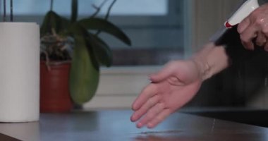 Adam, şişe spreyine bastıran dezenfektanla el temizliyor ve kağıt havlu tutuyor. Coronavirüs salgını sırasında elleri dezenfekte ediyor. COVID-19 salgını. Virüsün yayılması ile mücadele
