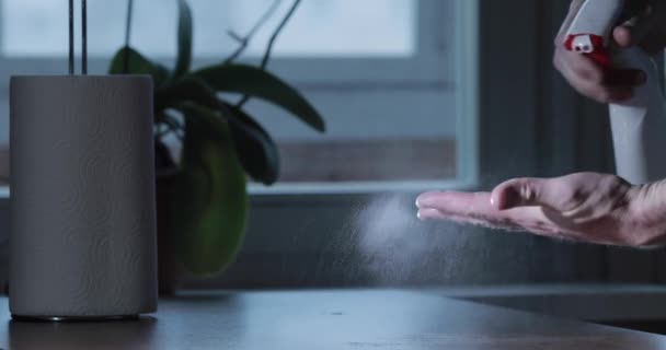 Чоловік чистить руки з дезінфікуючим засобом, натискаючи на пляшковий спрей і протирає руки паперовим рушником, дезінфікуючи шкіру рук під час пандемії коронавірусу, епідемії COVID-19. Боротьба з розповсюдженням вірусу — стокове відео