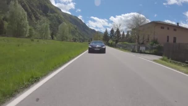 Italia, Alps, 15 Mayıs 2019: Yeni BMW 8 asfalt yolda, dağların arasındaki yeşil vadi, açık güneşli hava, ilerideki araç videosu, yüksek hız — Stok video