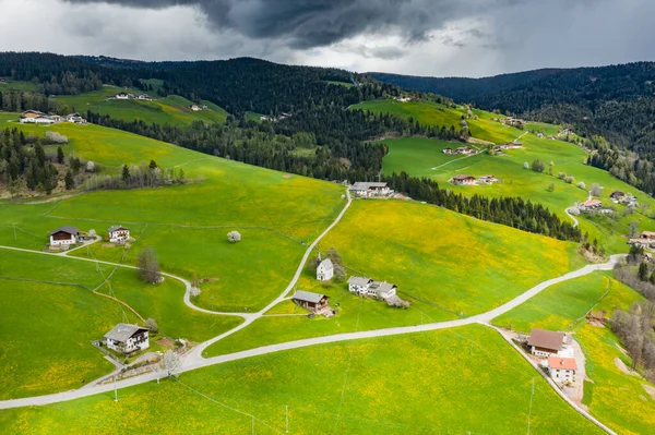 Aerial view of improbable green meadows of Italian Alps, green slopes of the mountains, Bolzano, huge clouds over a valley, roof tops of houses, Dolomites on background, sunshines through clouds — Stock Photo, Image