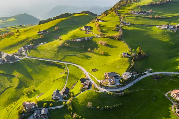 Aerial view of improbable green meadows of Italian Alps, green slopes of the mountains, Bolzano, huge clouds over a valley, roof tops of houses, Dolomites on background, sunshines through clouds — Stock Photo, Image