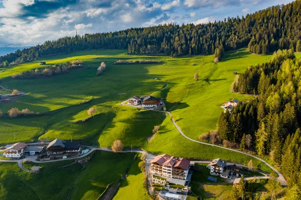 Aerial view of improbable green meadows of Italian Alps, green slopes of the mountains, Bolzano, huge clouds over a valley, roof tops of houses, Dolomites on background, sunshines through clouds — Stock Photo, Image