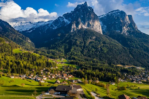 Aerial view of improbable green meadows of Italian Alps, green slopes of the mountains, Bolzano, huge clouds over a valley, roof tops of houses, Dolomites on background, sunshines through clouds — Stock Photo, Image