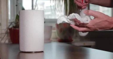 Adam dezenfektanla el temizliyor, şişe spreyine bastırıyor, kağıt havlu rulosu yapıyor, Coronavirüs salgını sırasında el derisini dezenfekte ediyor, COVID-19 salgını. Virüsün yayılması ile mücadele