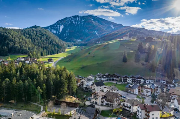 Vadi manzaralı, kiliseli küçük şehir, İtalya dağlarının yeşil yamaçları, Badia 'daki Trentino, San Martino, yerleşim yerlerinin çatıları, yeşil çayırlar, arka plandaki Dolomitler.,