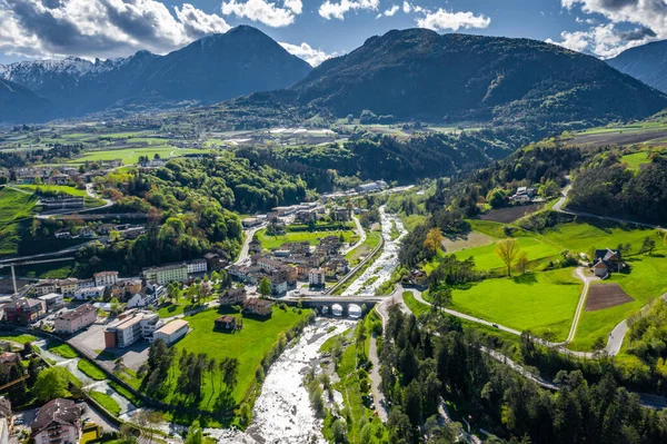 Légi kilátás völgy Cares, Trentino, zöld lejtők a hegyek Olaszország, hatalmas felhők a völgy felett, tető tetején házak, Dolomitok a háttérben, hidak, folyó és utak, tavaszi színek — Stock Fotó