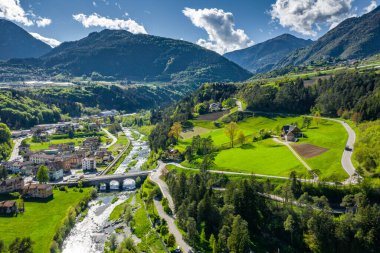 Vadi manzarası Cares, Trentino, İtalya 'nın yeşil yamaçları, vadinin üzerindeki dev bulutlar, evlerin çatıları, arka plandaki Dolomitler, köprüler, nehir ve yollar, bahar renkleri.