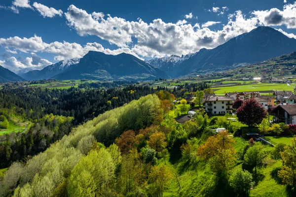 Aerial view of valley Cares, Trentino, green slopes of the mountains of Italy, huge clouds over a valley, roof tops of houses, Dolomites on background, bridges, river and roads, spring colors — Stock Photo, Image