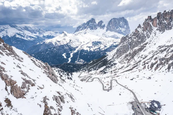 Vista aérea de la carretera torcida en las montañas de Italia, Dolomitas, es serpentina entre las colinas cubiertas de nieve, es famoso lugar entre los esquiadores y aficionados a entender un conocido por los coches deportivos, pico de las montañas — Foto de Stock