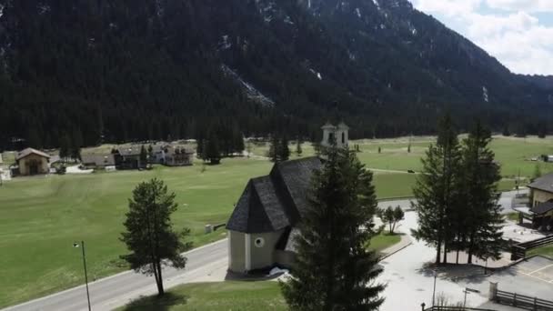 Luftaufnahme des Tals mit der Kirche Unserer Lieben Frau vom Karmel, grüne Hänge der Berge Italiens, Trentino, Fontanazzo, grüne Wiesen, Dolomiten im Hintergrund — Stockvideo