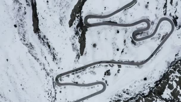 イタリア、ドロマイトの山の中で曲がりくねった道の空中ビューは、雪に覆われた丘の間で蛇行され、スポーツカー、山のピークで知られている理解するためにスキーヤーやファンの間で有名な場所です — ストック動画