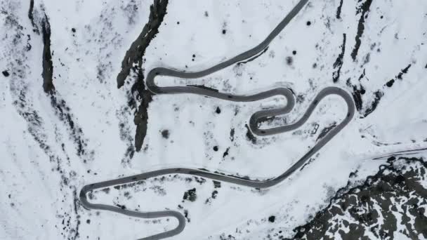イタリア、ドロマイトの山の中で曲がりくねった道の空中ビューは、雪に覆われた丘の間で蛇行され、スポーツカー、山のピークで知られている理解するためにスキーヤーやファンの間で有名な場所です — ストック動画