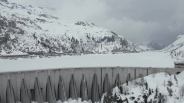 Avusturya 'nın güneyinde veya kuzey İtalya' da karla kaplı bir barajın üzerinden uçan insansız hava aracının videosu Trentino, bir baraj yolu boyunca uzanan göl ve dağlar boyunca uzanan bir yoldur.