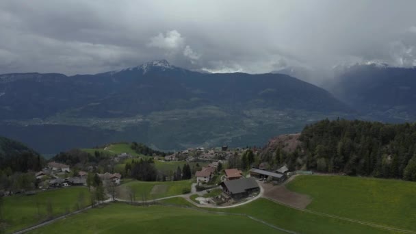 Olağandışı yeşil İtalyan Alpleri çayırları, dağların yeşil yamaçları, Bolzano, vadideki devasa bulutlar, evlerin çatıları, arka planda Dolomitler, bulutların arasından gün ışığı. — Stok video
