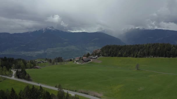 Вид с воздуха на невероятные зеленые луга итальянских Альп, зеленые склоны гор, Больцано, огромные облака над долиной, крыши домов, Доломиты на заднем плане, солнечные лучи сквозь облака — стоковое видео