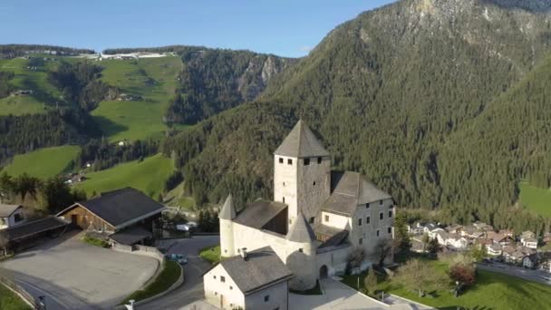 Luftaufnahme des Tals mit Kirche bei Sonnenuntergang, grüne Hänge der Berge von Italien, Trentino, Südtirol, grüne Wiesen, Dolomiten im Hintergrund, Drohne fliegt herum — Stockvideo