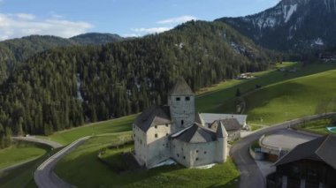 Gün batımında kilisesi olan vadi manzarası, İtalya, Trentino, Güney Tyrol dağlarının yeşil yamaçları, yeşil çayırlar, arka planda Dolomitler, insansız hava aracı uçuşları.