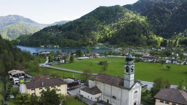 The Improbable aerial landscape of Molveno, is a comune in Trentino in the northern Italian region of Trentino-Alto Adige, church of San Carlo Borromeo, sunny weather, a piers, coastline, — Stock Video