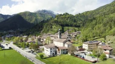 Molveno 'nun Olasılıkdışı hava manzarası, İtalya' nın Trentino-Alto Adige bölgesinde, San Carlo Borromeo kilisesi, güneşli hava, bir rıhtım ve kıyı şeridi.,