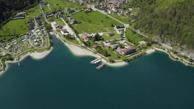 Molveno 'nun Olasılıkdışı hava manzarası, İtalya' nın Trentino-Alto Adige bölgesinde, San Carlo Borromeo kilisesi, güneşli hava, bir rıhtım ve kıyı şeridi.,