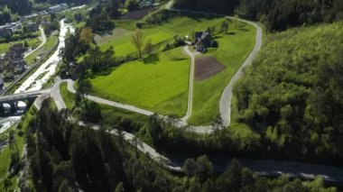 Yeşil bir çayır, vadi, Trentino, İtalya dağlarının yeşil yamaçları, evlerin çatıları, arka planda Dolomitler, köprüler, nehir ve yollar, bahar renkleri.