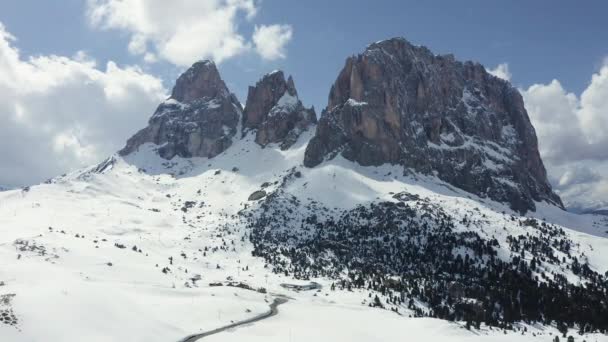Luftaufnahme der schneebedeckten Dolomiten in Italien bei sonnigem Wetter, Canazei, Drohnenaussichtspunkt, kurvenreiche Straße, blauer Himmel mit weißen Wolken, berühmter Ort der Welt, UNESCO-Denkmal — Stockvideo