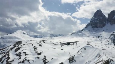 İtalya, Dolomitler, Canazei, 10 Mayıs 2019: Uçan dron, arka planda karla kaplı dağlar, kıvrımlı yollar, beyaz bulutlu mavi gökyüzü, güneşli hava
