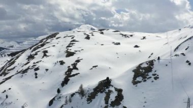Dolomitlerin güneşli bir günde İtalya 'da karla kaplı dağların havadan görünüşü, Canazei, insansız hava aracı bakış açısı, kıvrımlı yol, beyaz bulutlu mavi gökyüzü, dünyada ünlü bir yer, UNESCO anıtı.